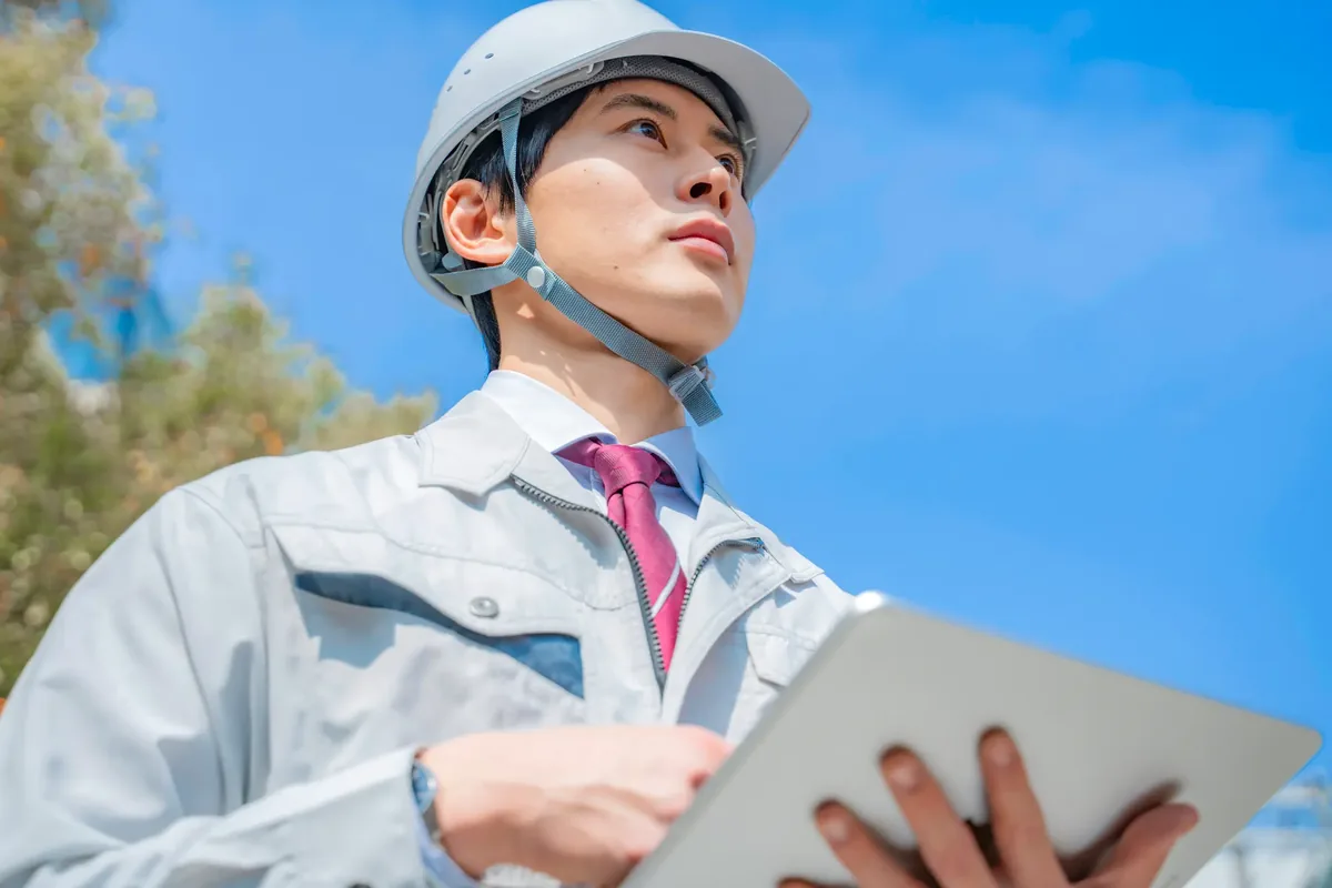 タブレットを手に現場で作業する若手の建設作業員