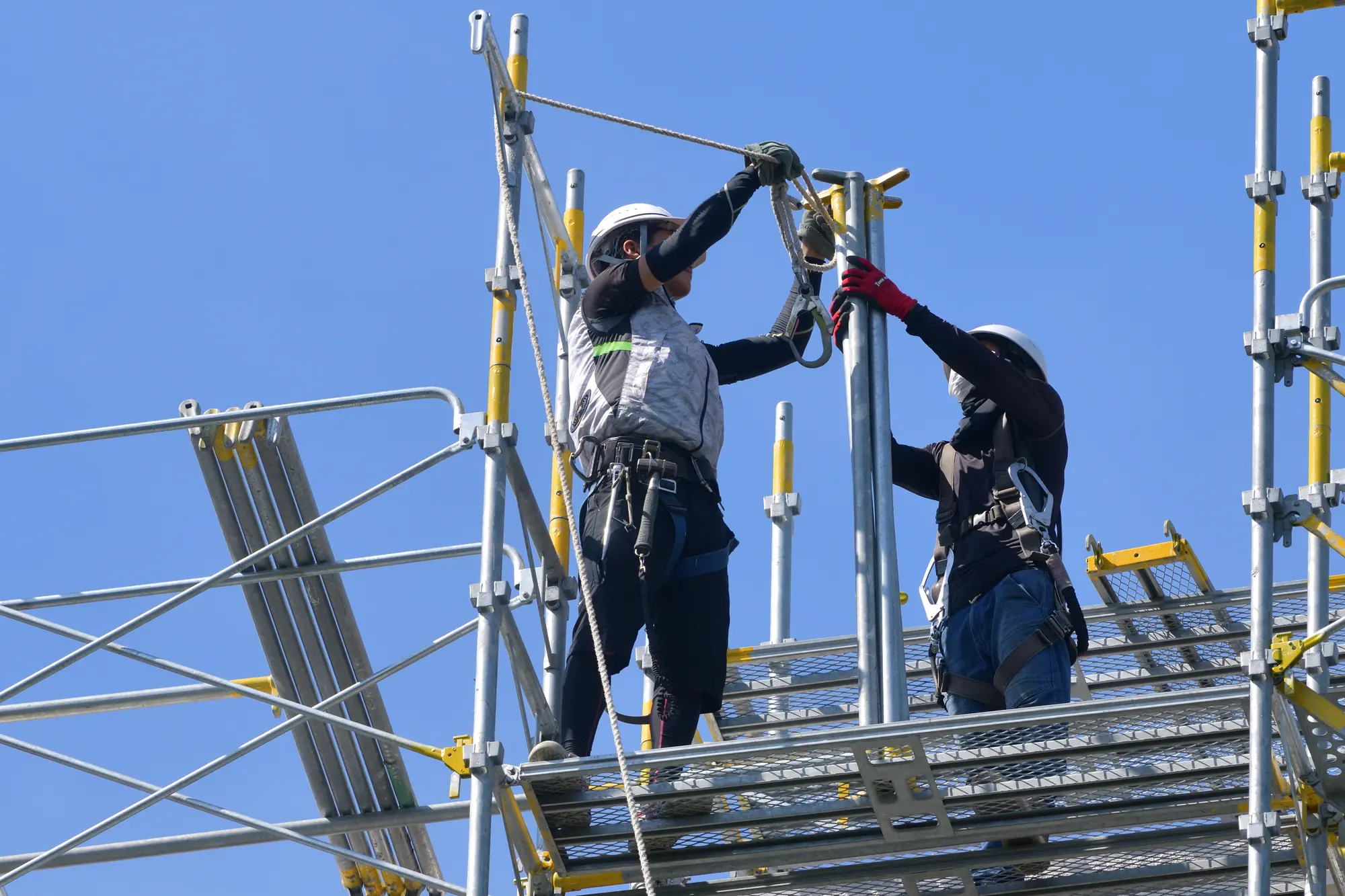 足場で安全設備を確認する建設作業員
