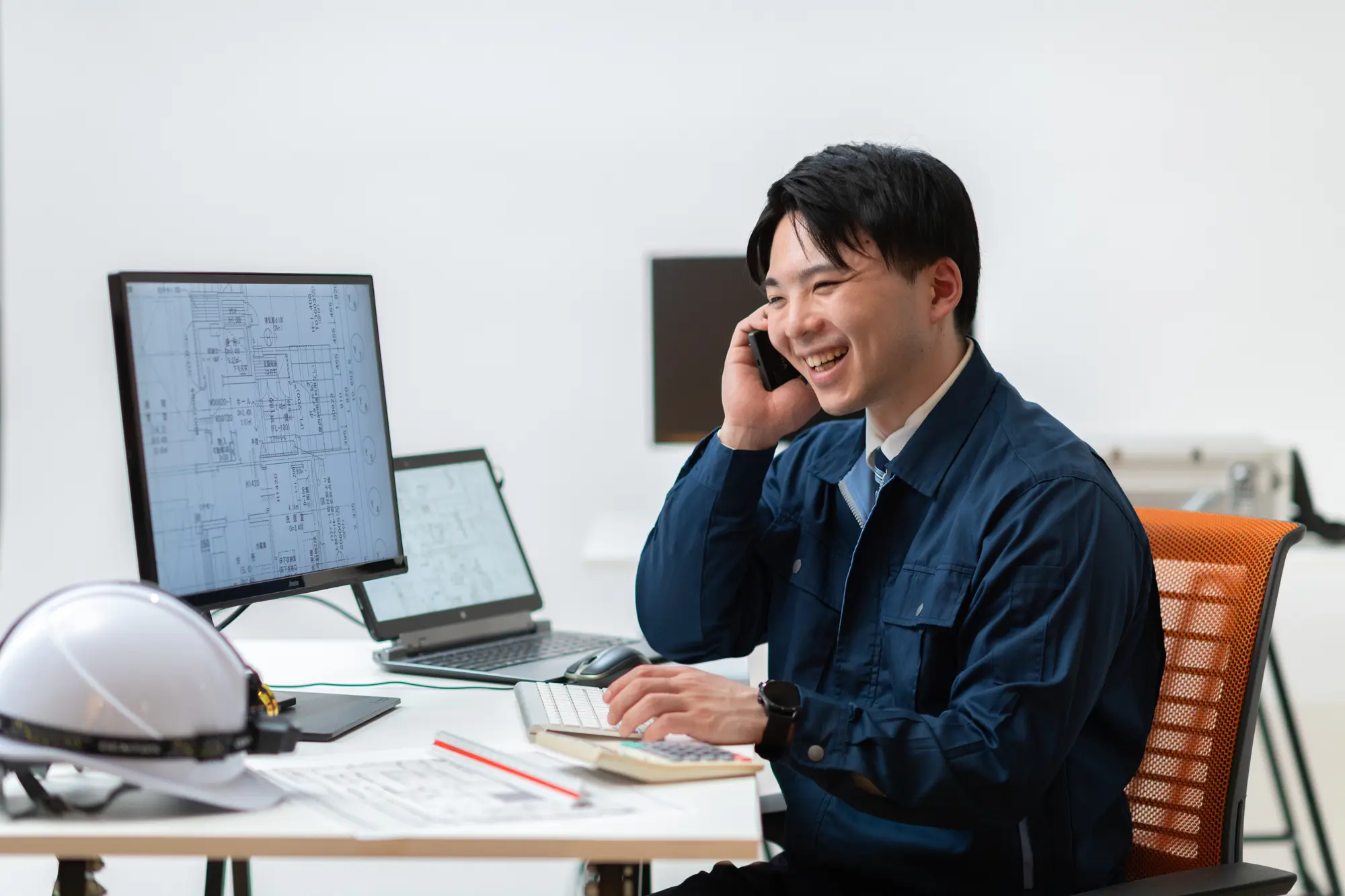 図面を確認しながら電話対応する建設会社の社員